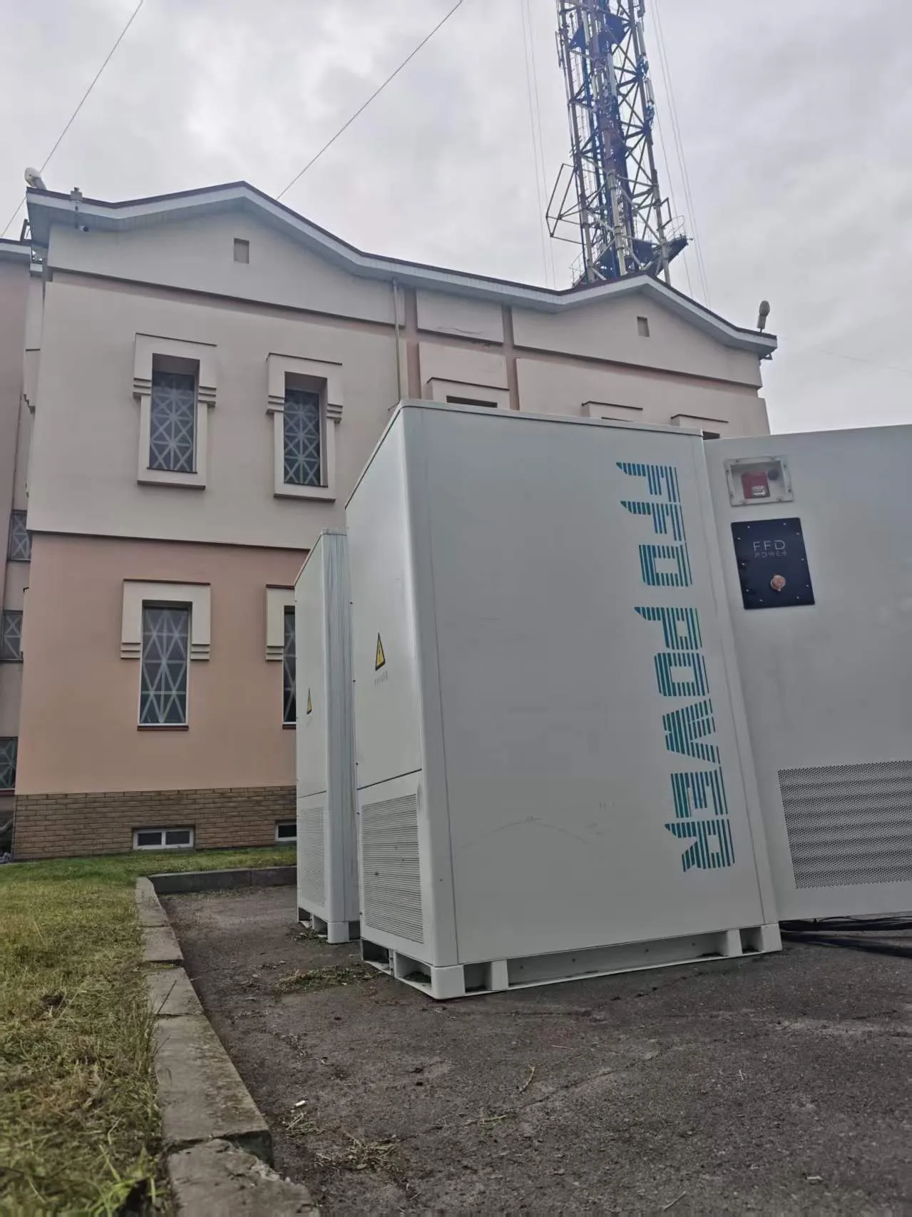 FFD POWER Batterieschränke neben einem historischen Gebäude mit Sendemast im Hintergrund