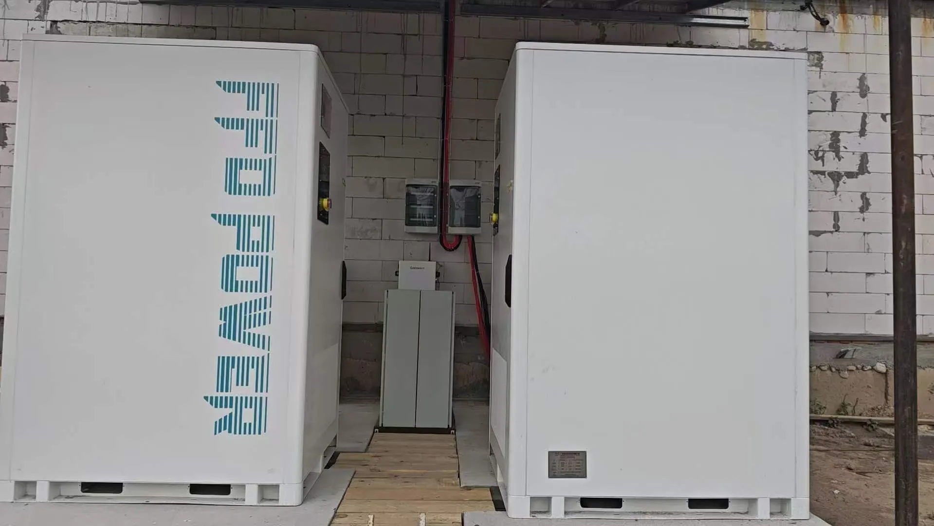 Zwei FFD POWER Batterieschränke gegenüberliegend in einem Ziegelgebäude, mit einem kleineren Steuerschrank dazwischen