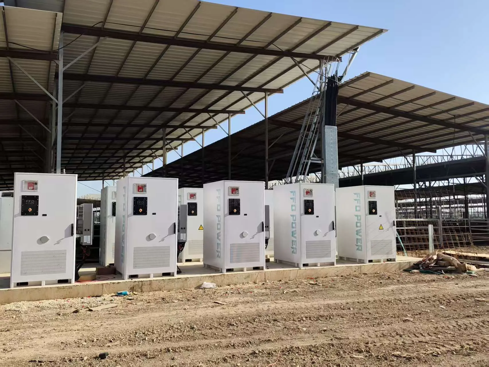 Reihe von FFD POWER Batterieschränken auf einem Betonfundament unter einer großen Industriedach-Konstruktion