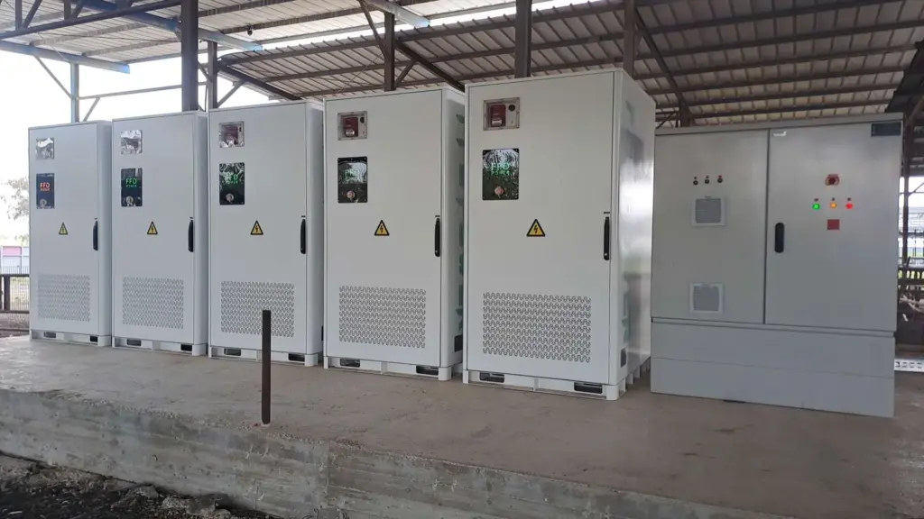 FFD POWER Batterieschränke unter einem überdachten Unterstand, daneben ein größerer Steuerungsschrank mit Statusanzeigen