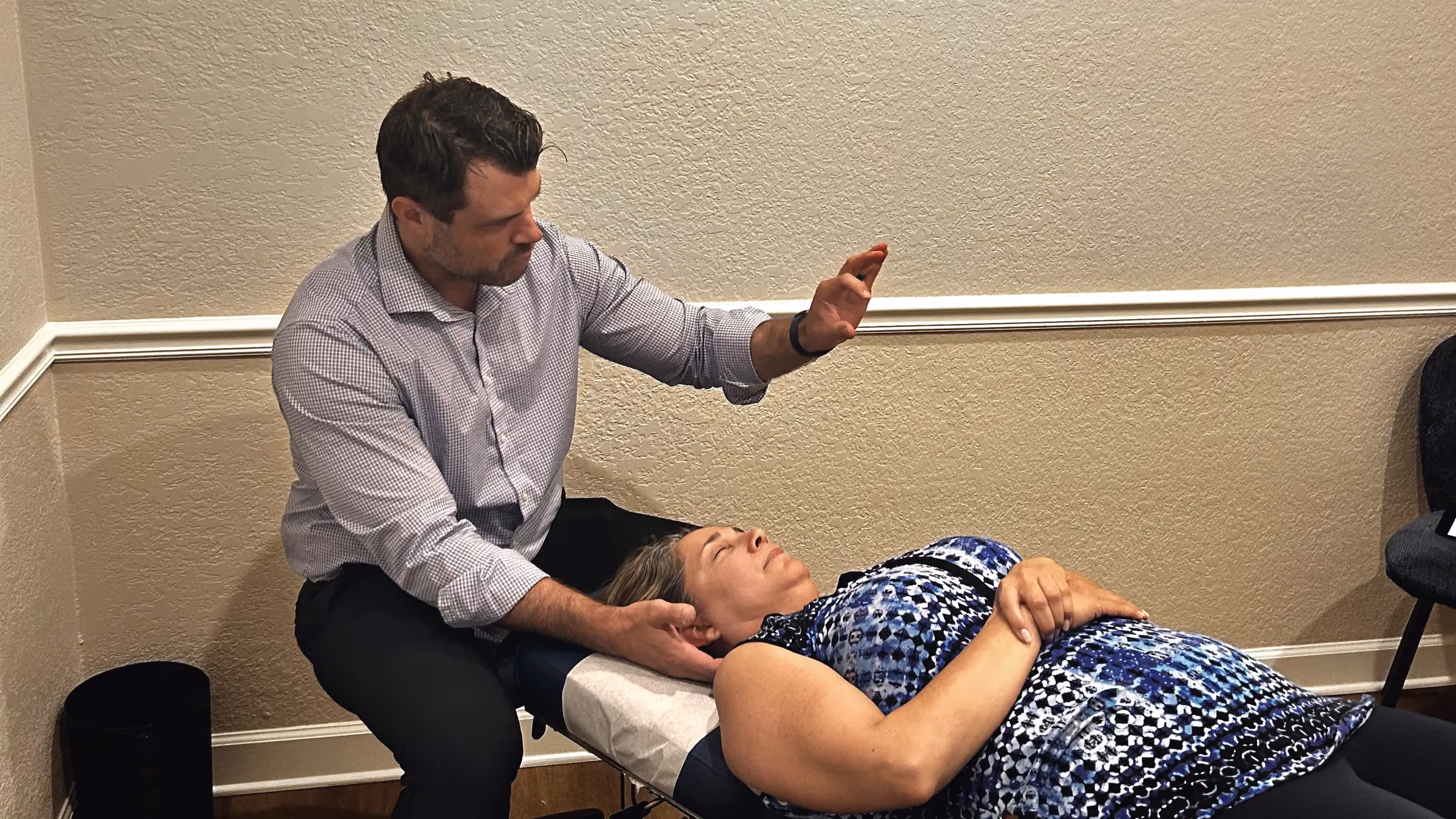 Chiropractor treating the neck of a patient lying face up
