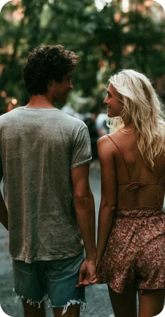 Four friends closely gathered around a smartphone, smiling and sharing a moment outside.
