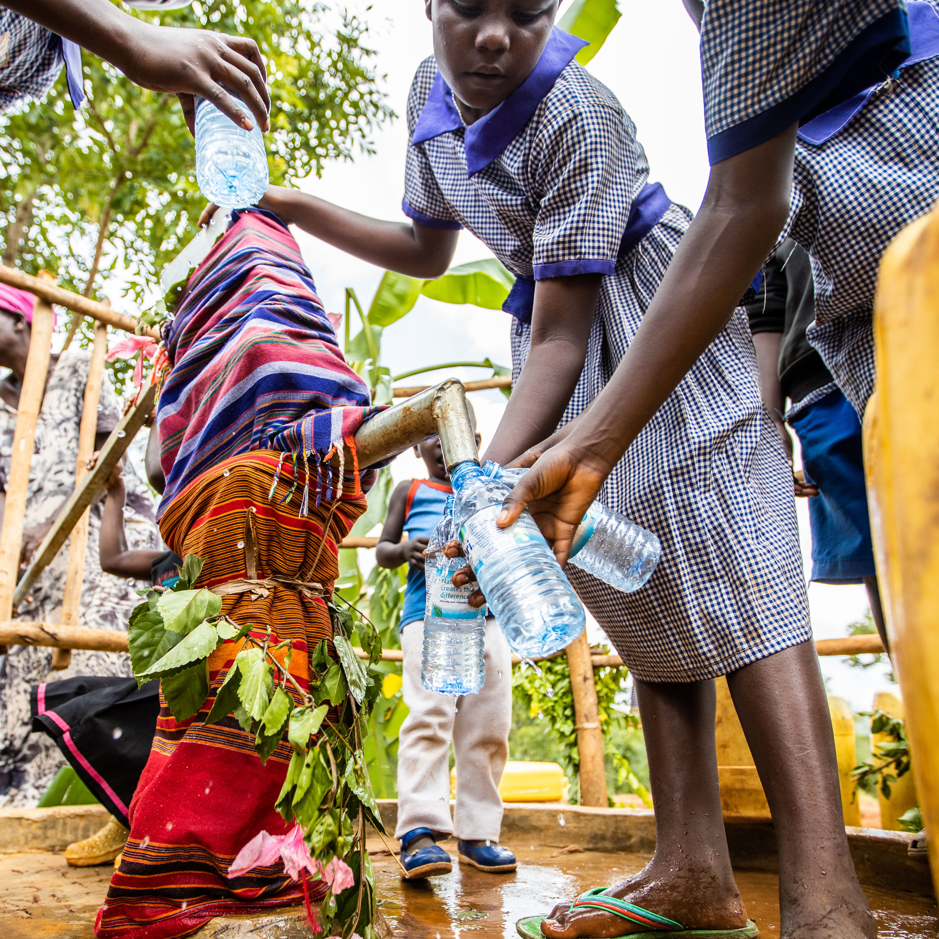 Schoolchildren filling bottles at a community water point in Nebbi District, Uganda