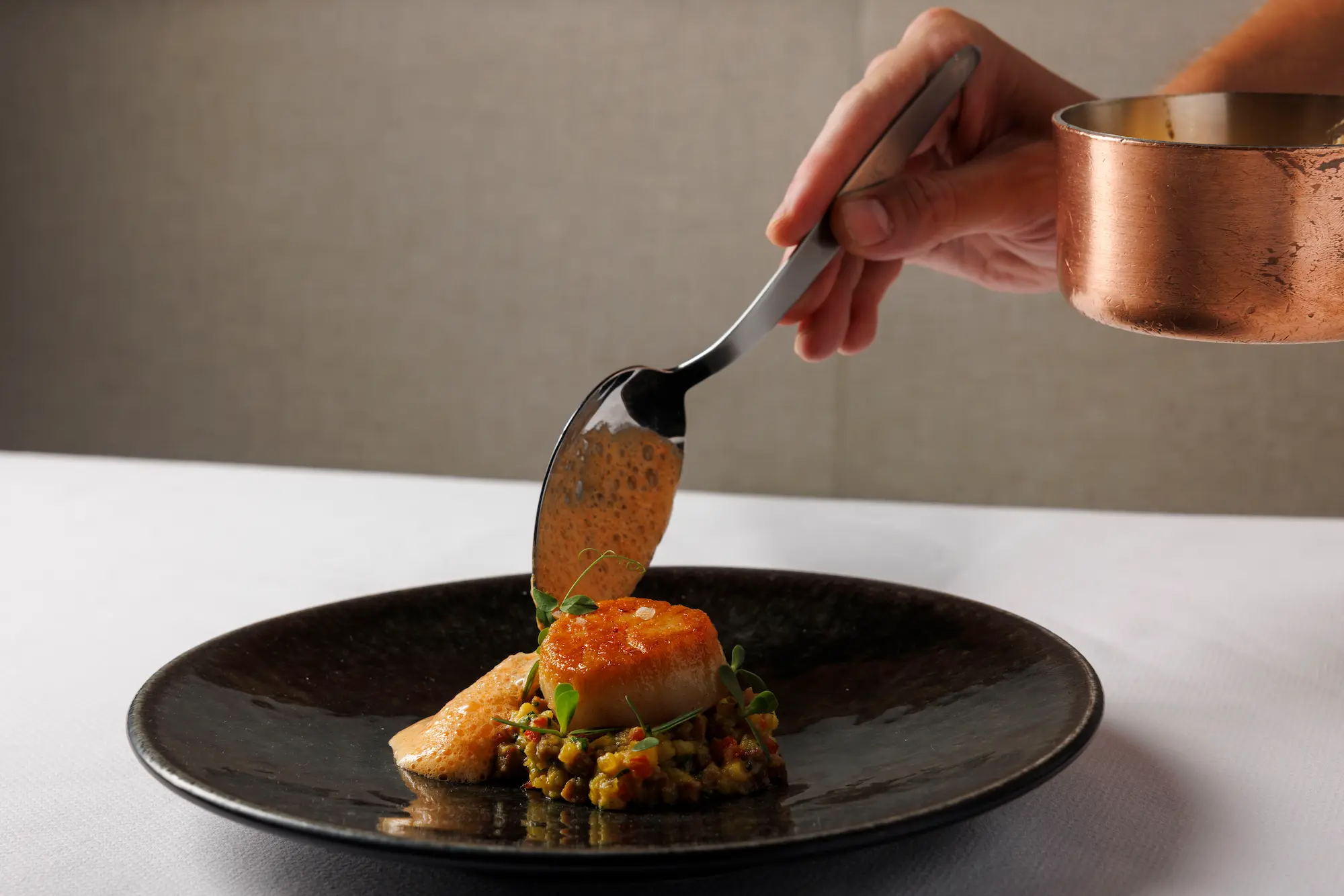 Chef carefully plating a seasonal tasting menu course at Amphora, a wine-focused fine dining restaurant in Manhattan’s Flatiron District.