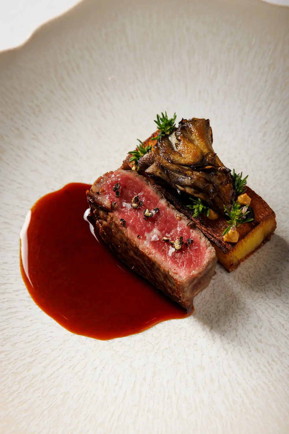 Dry-aged ribeye with roasted mushrooms, potato terrine, and bordelaise sauce served as a seasonal tasting menu course at Amphora in Manhattan’s Flatiron District.