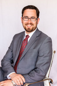 Professional headshot of David A. O'Neill, smiling, wearing a gray suit with a red patterned tie.