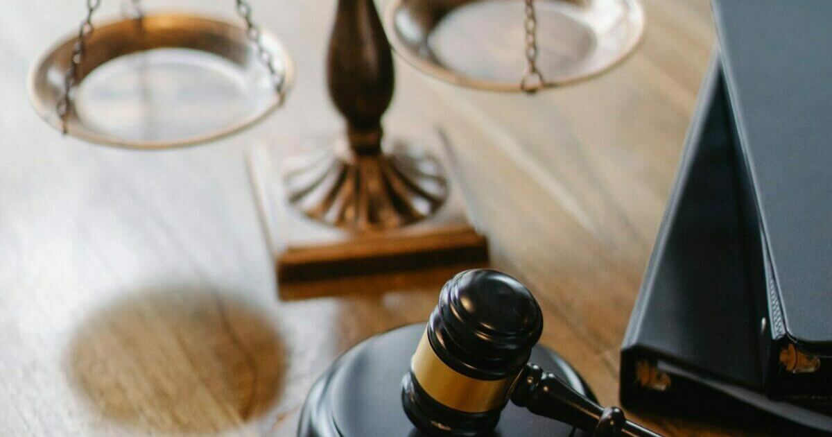 A balance in the background and a hammer and gavel in the foreground