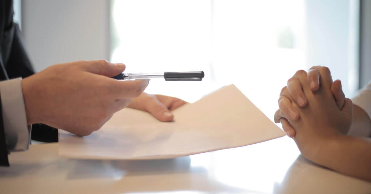 Two people sitting at a desk reviewing a contract together before signing