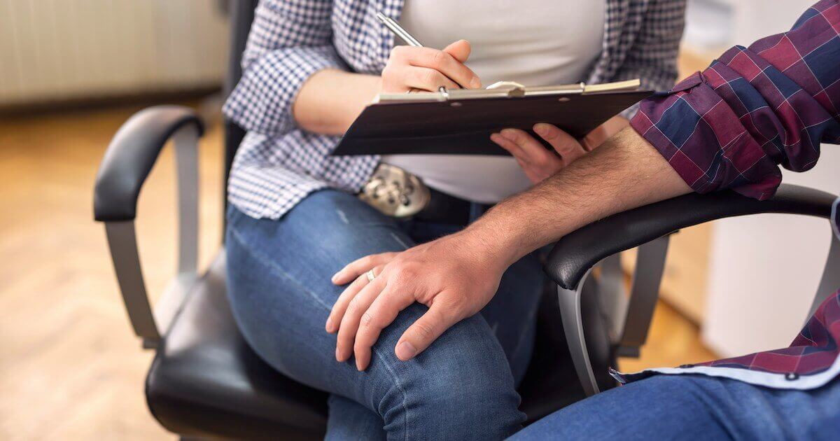 A male colleague inappropriately rests his hand on a female colleague's thigh