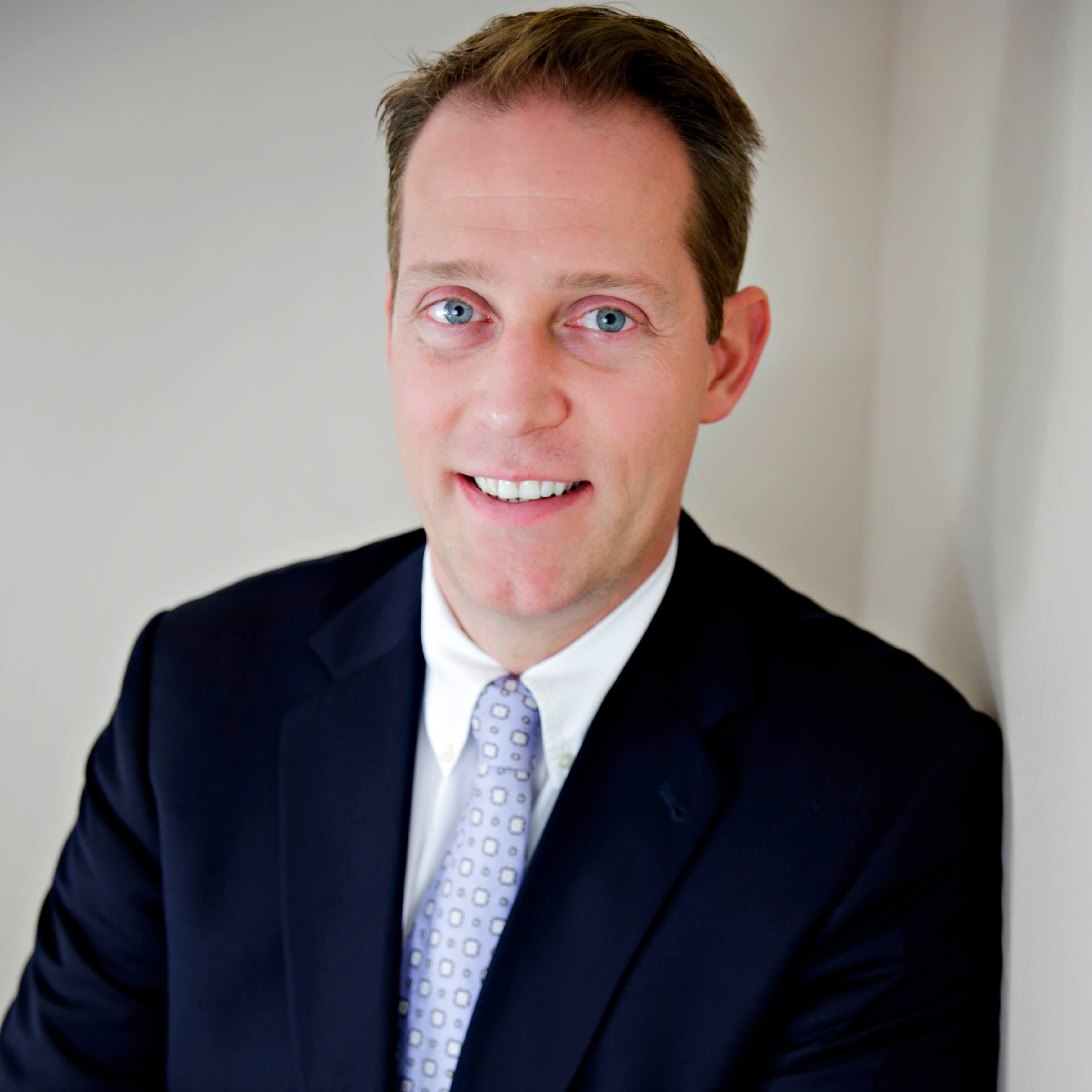 Headshot of a blue eyed man wearing a suit and tie