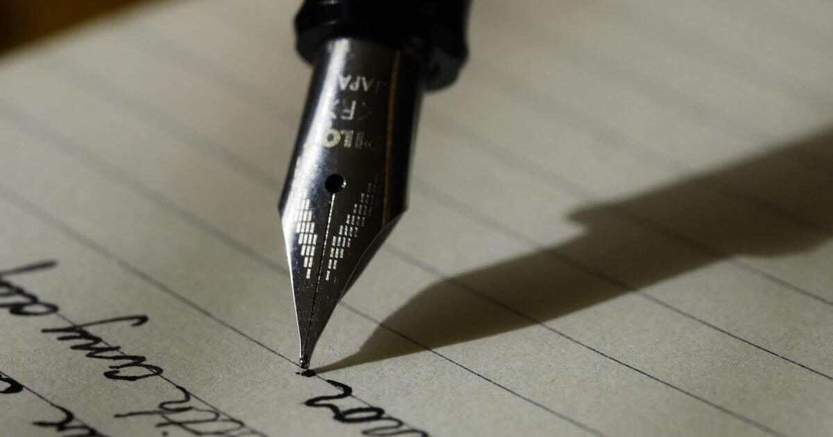 A fountain pen writing on paper in cursive