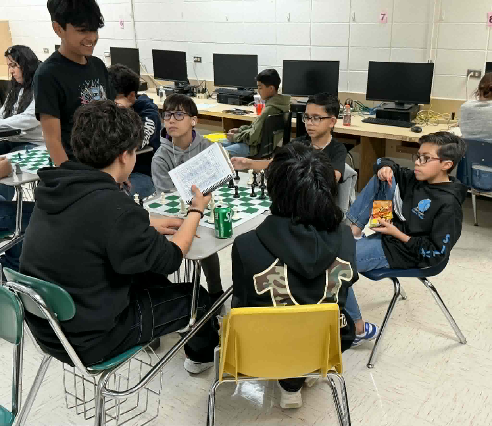 Students discussing chess tactics and reviewing scoresheets together during a youth chess club session. Shared by RGV Chess and Learning Center.