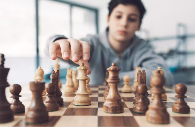 Close-up action shot of a student executing a strategic move on a wooden chess board. Shared by RGV Chess and Learning Center