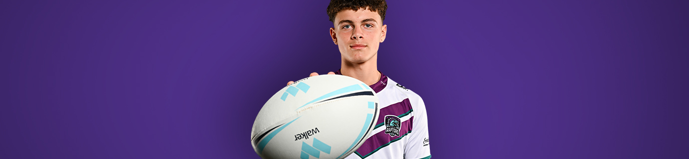 Junior rugby player in a purple and white jersey holding a rugby ball against a purple backdrop