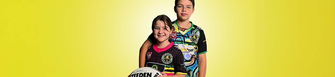 Three junior rugby league players in green and gold club jerseys standing with arms crossed against a green backdrop