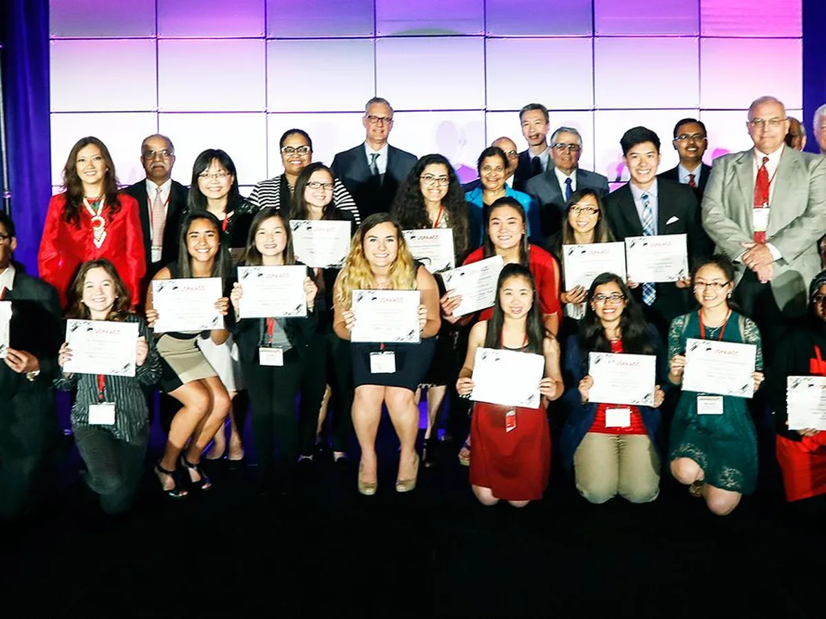 USPAACC College Scholarship recipients holding their certificates on stage at CelebrASIAN