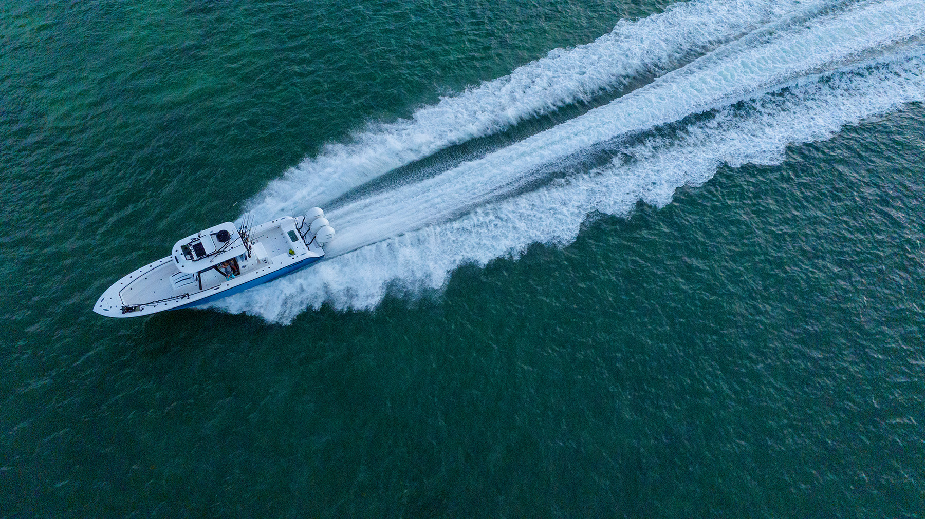 Drone view of a coated center console running wide open across green water