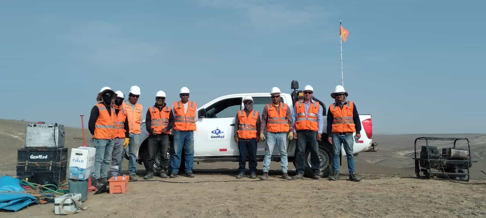 Equipo de campo con chalecos de seguridad y cascos junto a una camioneta en terreno abierto