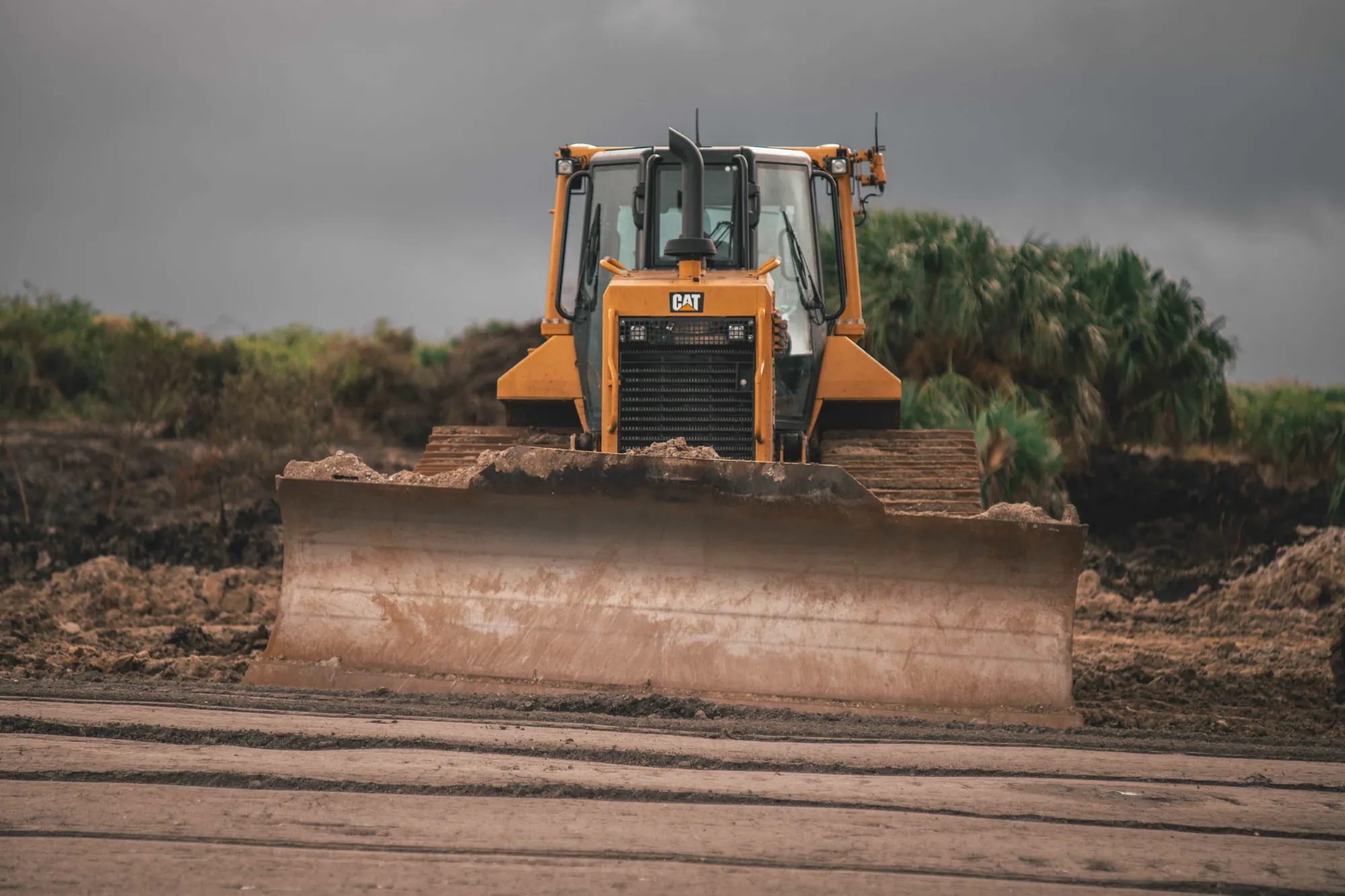 Bulldozer despejando terreno junto a vegetación tropical