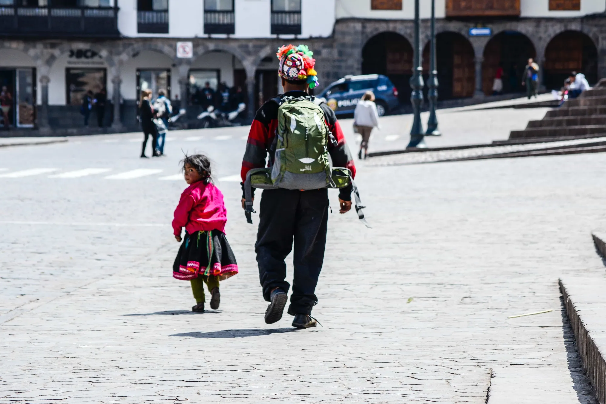 Un adulto y un niño cruzan una plaza empedrada
