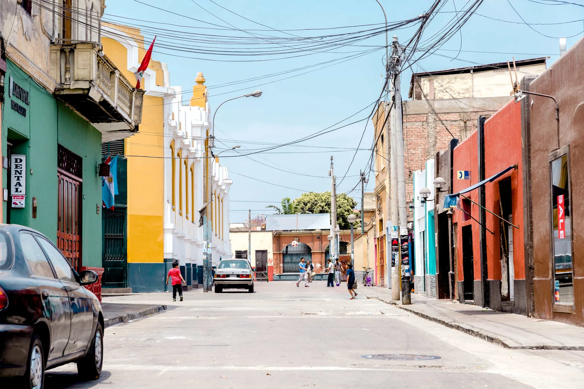 Colourful street in a Peruvian town with residents walking and parked cars