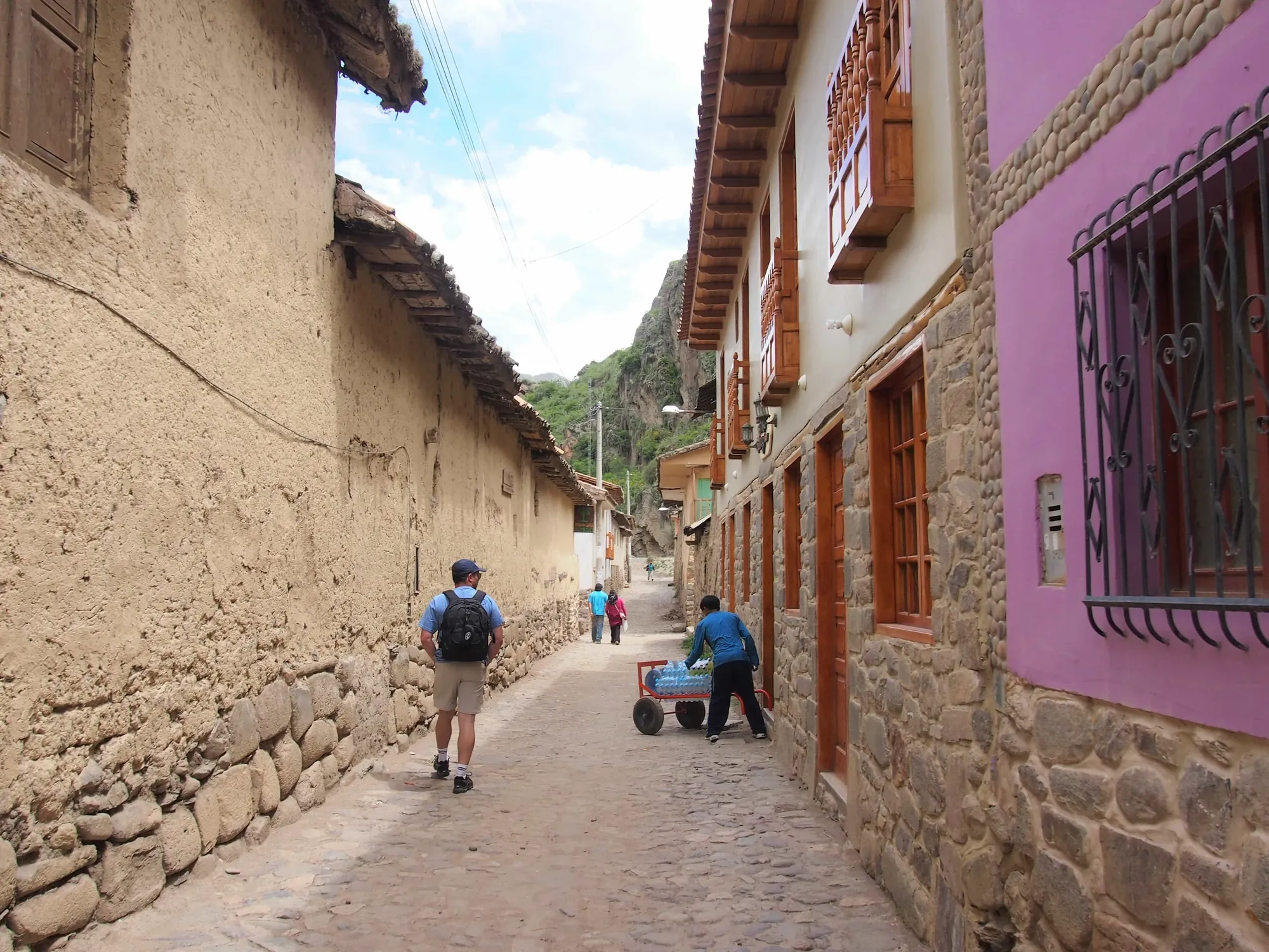 Pobladores caminando por una calle estrecha entre casas pintadas