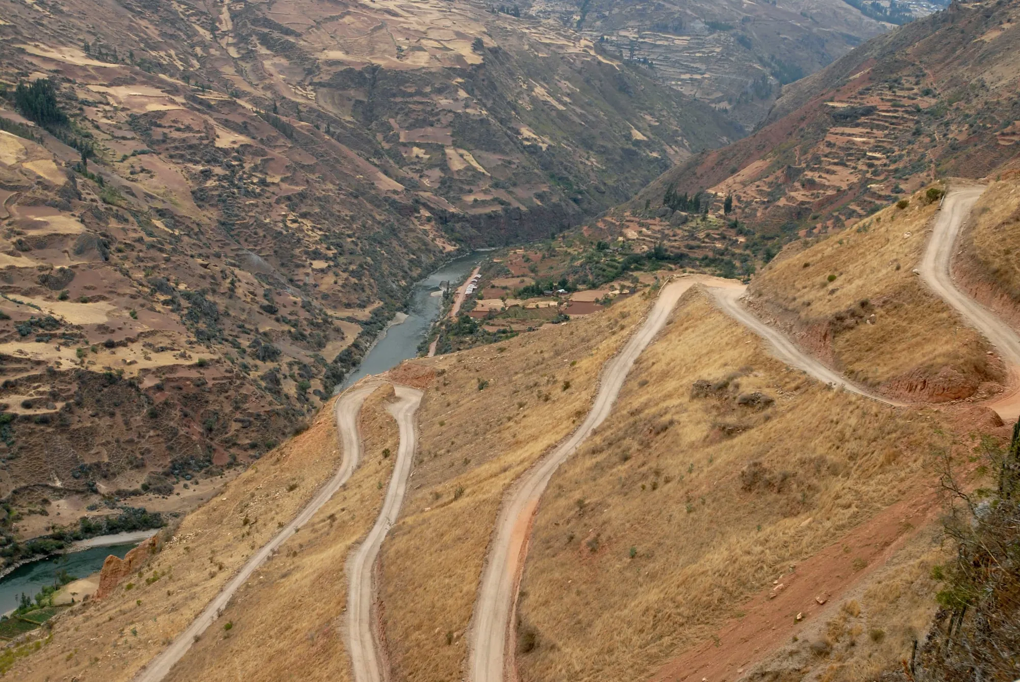 Vista aérea de caminos en zigzag en una ladera empinada sobre un valle fluvial