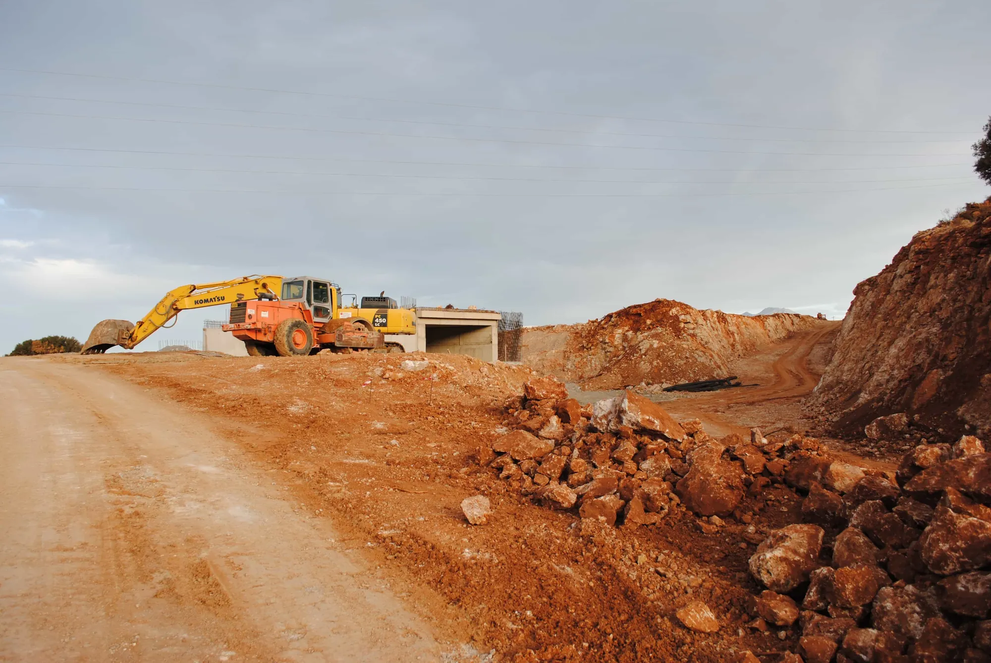 Excavadora trabajando tierra roja en un sitio a cielo abierto