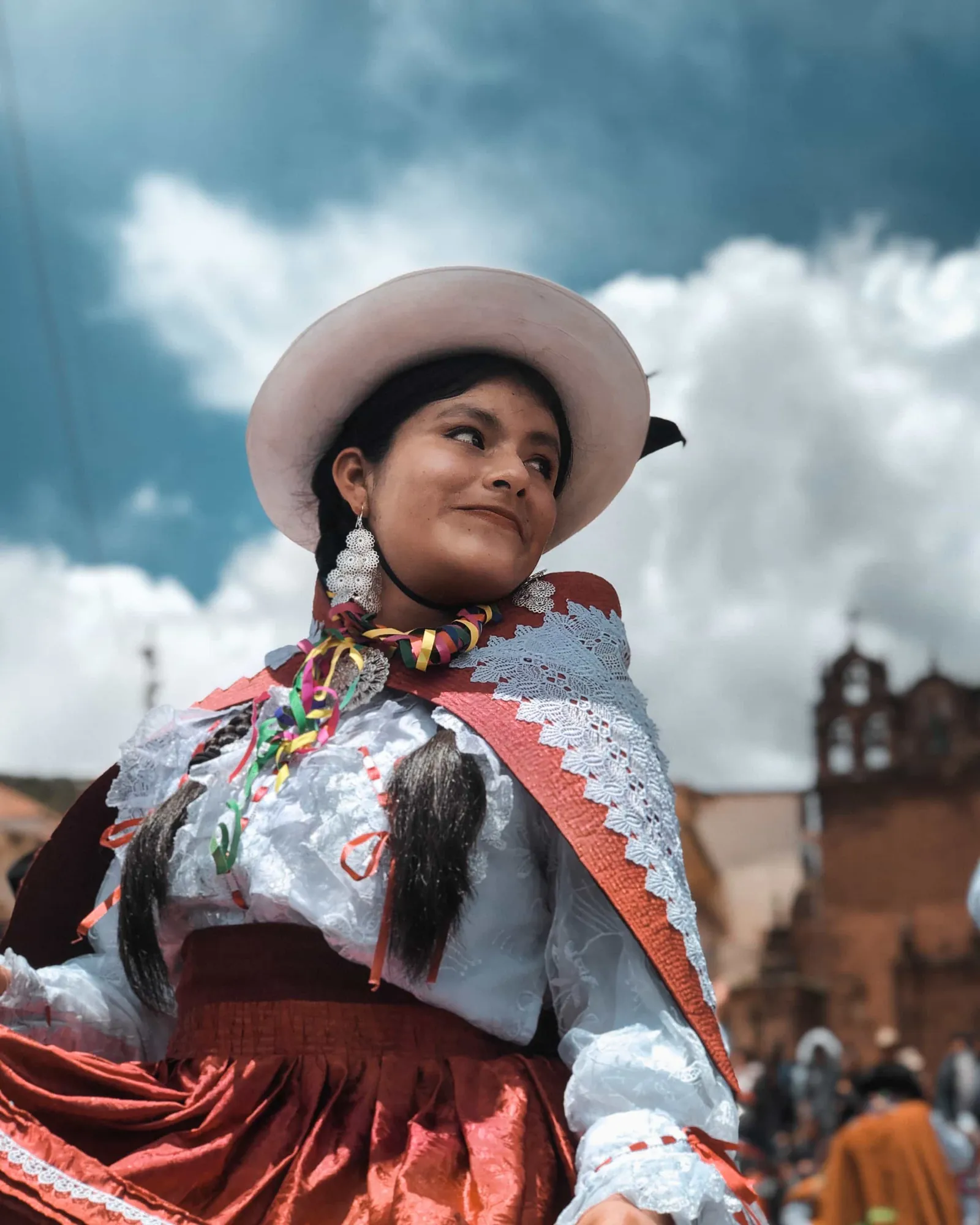 Mujer de pie en su puesto de mercado rodeada de textiles artesanales