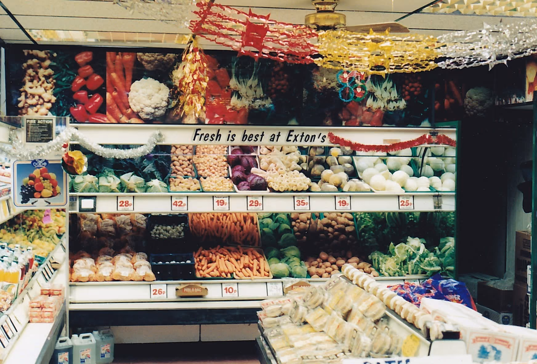 Grocery store produce section with vegetables and sign reading 'Fresh is best at Exton’s'.