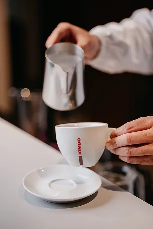 Barista sipa mleko u šoljicu kafe u Kimbo trening centru za edukaciju.