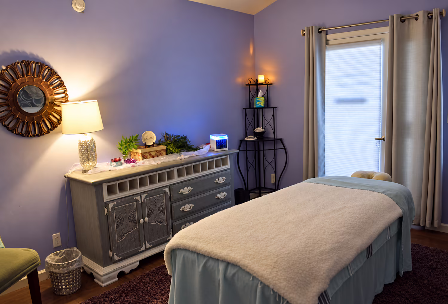 Treatment room with a massage table, mirror and soft lighting
