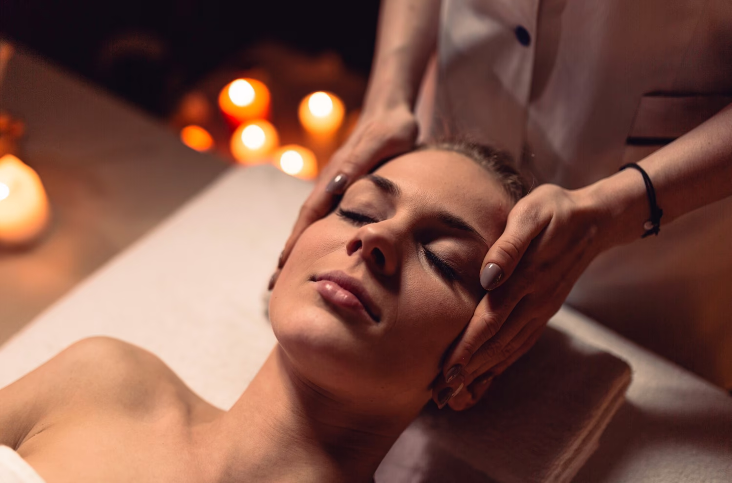 Woman receiving a face and head massage by candlelight