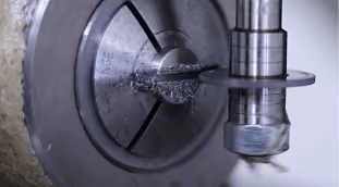 Metal lathe machine cutting a cylindrical metal piece with metal shavings forming.