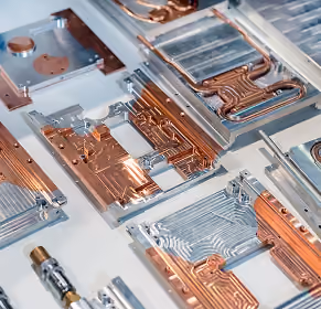 Close-up of various copper heat sinks with intricate pathways on a white surface.