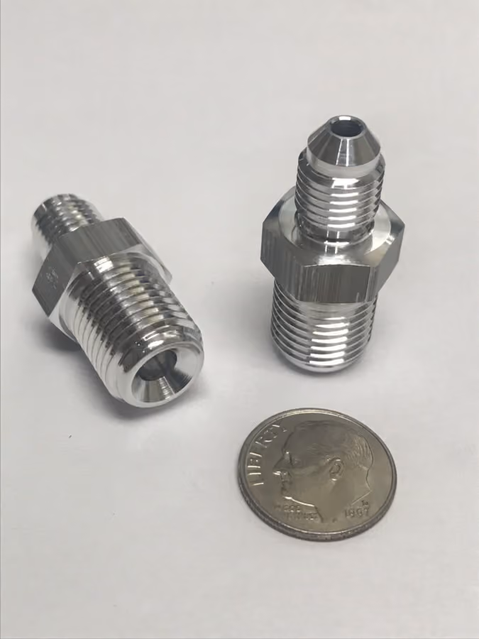Two shiny metal threaded fittings next to a US dime on a white surface.