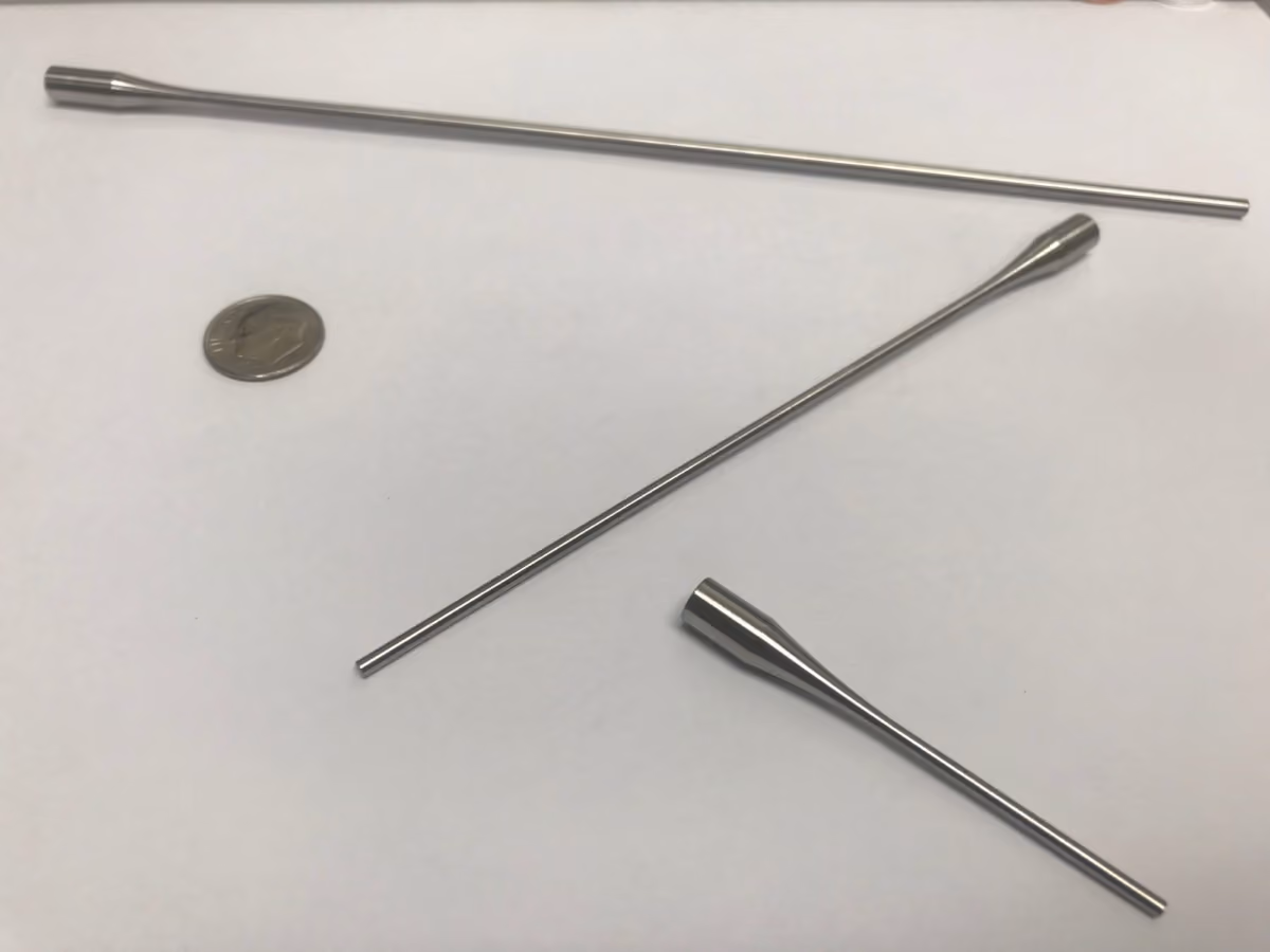 Three stainless steel tubes of different lengths and a US dime on a white surface.