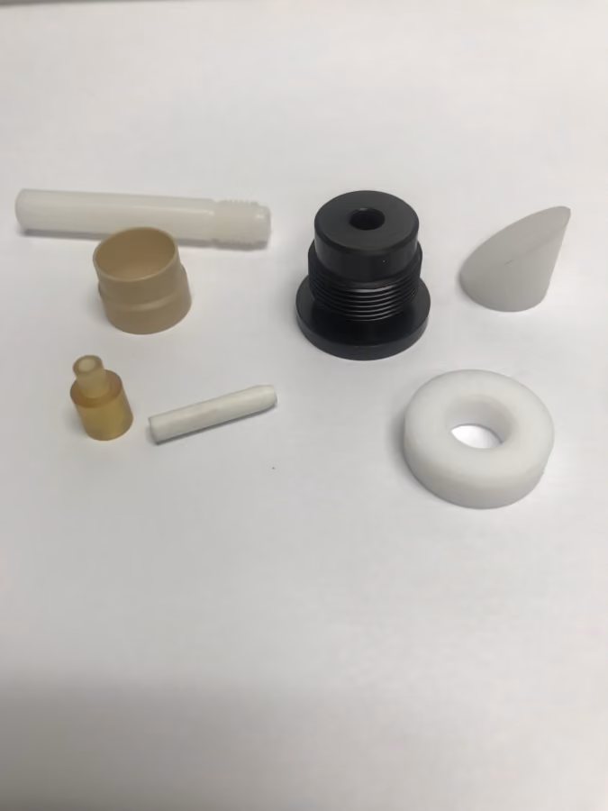 Various small plastic and metal mechanical parts arranged on a white surface.