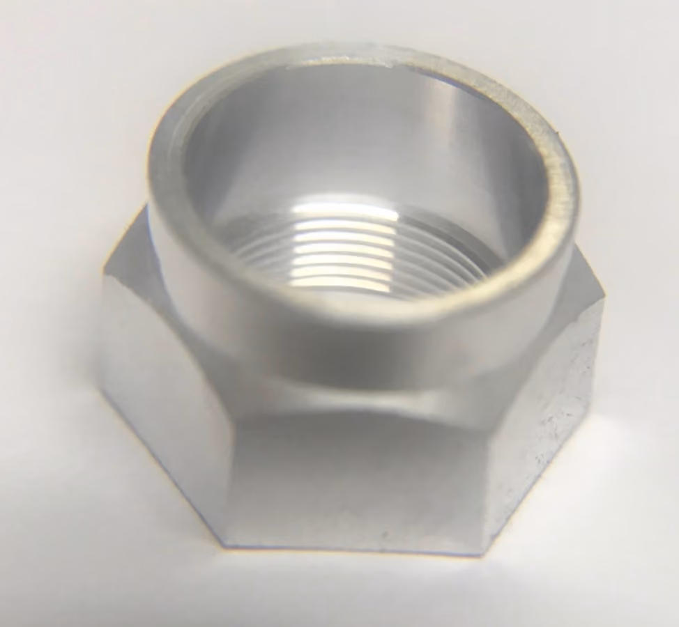 Close-up of a shiny metal hex nut with internal threading on a white background.