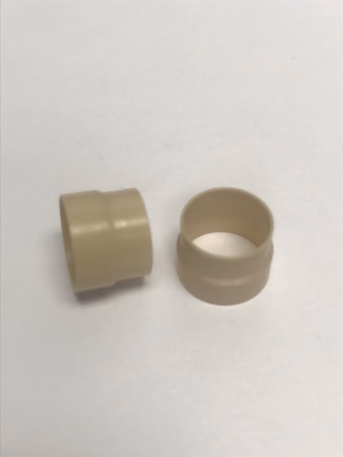 Two small beige plastic cylindrical spacer bushings on a white background.