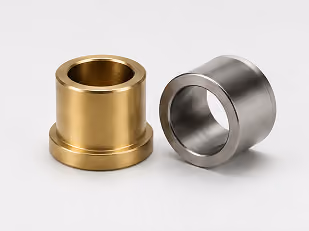 Two cylindrical metal bushings, one brass-colored and one silver-colored, on a white surface.