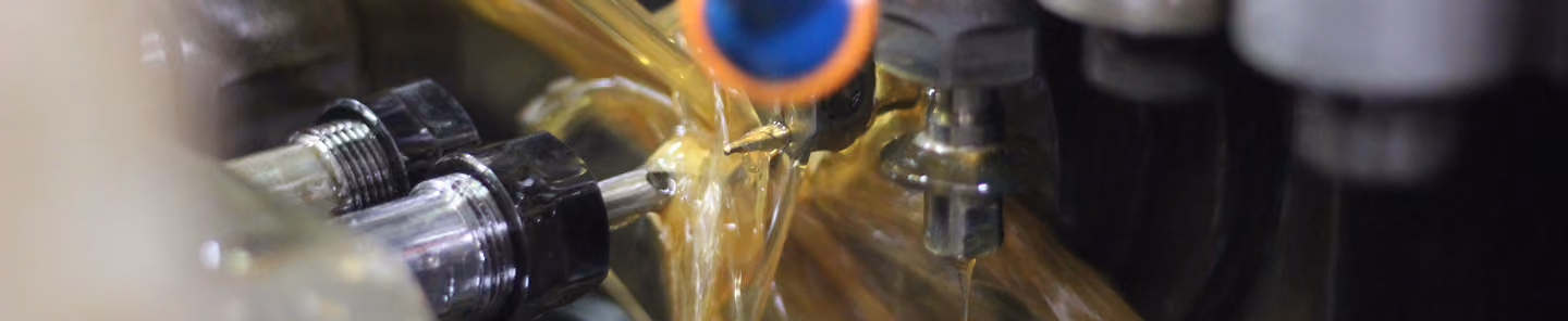 Coolant fluid pouring on metal parts during precision machining process.