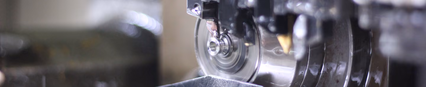 Close-up of a metal grinding wheel sharpening a tool, with sparks and blurred background.
