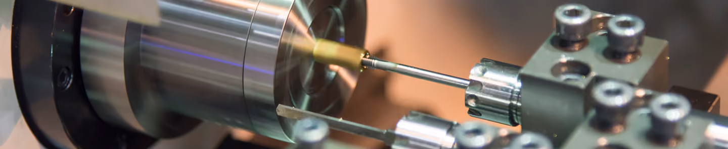 Close-up of a metal lathe machine shaping a cylindrical metal piece.