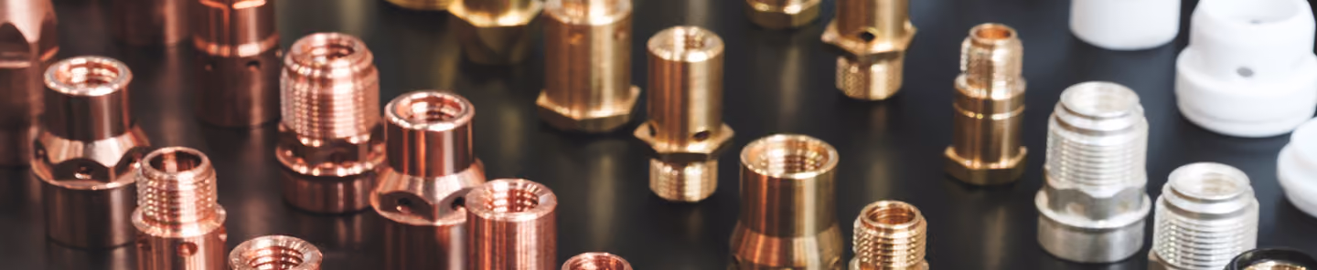 Various small metal threaded fittings and connectors arranged on a dark surface.