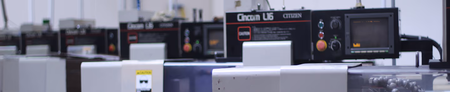 Close-up of industrial CNC machines with screens and control buttons in a factory setting.