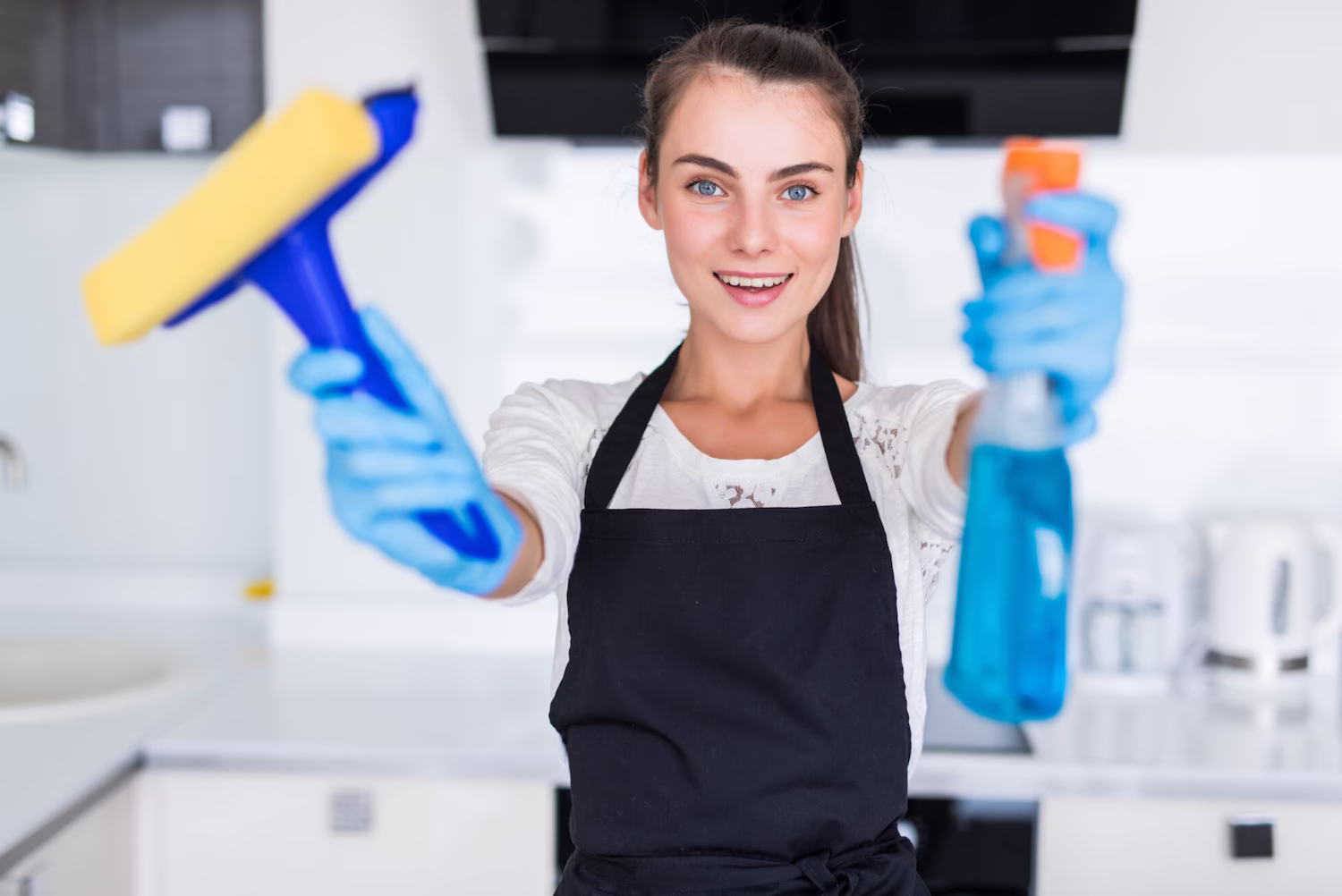 Cleaner in gloves holding a squeegee and spray bottle