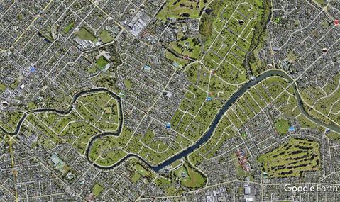 Satellite view of a suburb with a river and a corridor of green open space running through it.