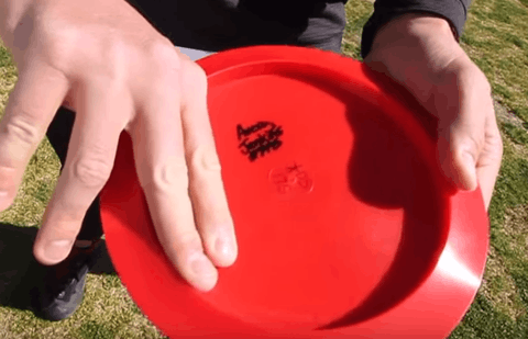 A staggered finger grip on a red disc, the fingers stepped along the underside of the rim.
