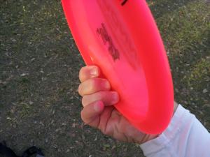 A three-finger power grip on a pink disc, three fingers under the rim.